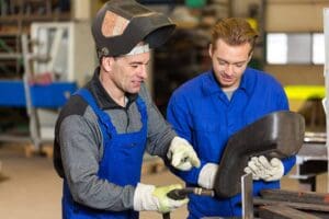 Instructor teaching trainee how to weld metal