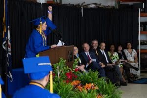 Graduate at podium with her hand in the air.