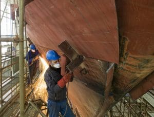 Welding new steel plates on a ship's hull during repair work on a ship in a dry dock.