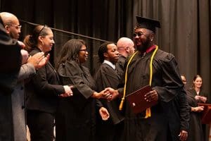 A proud Tidewater Tech graduate walking across the stage, shaking hands with the faculty.
