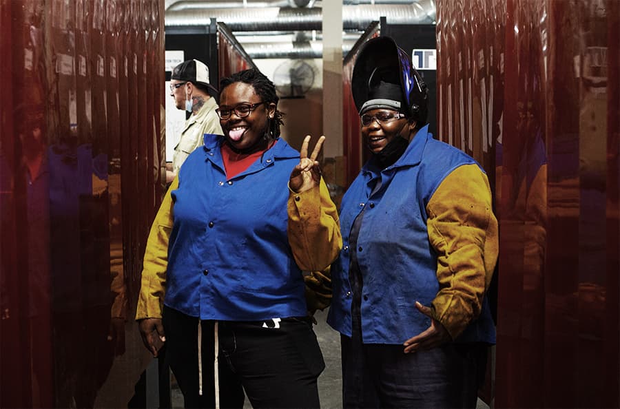 Two Tidewater Tech welding students smiling and posing in the welding lab.