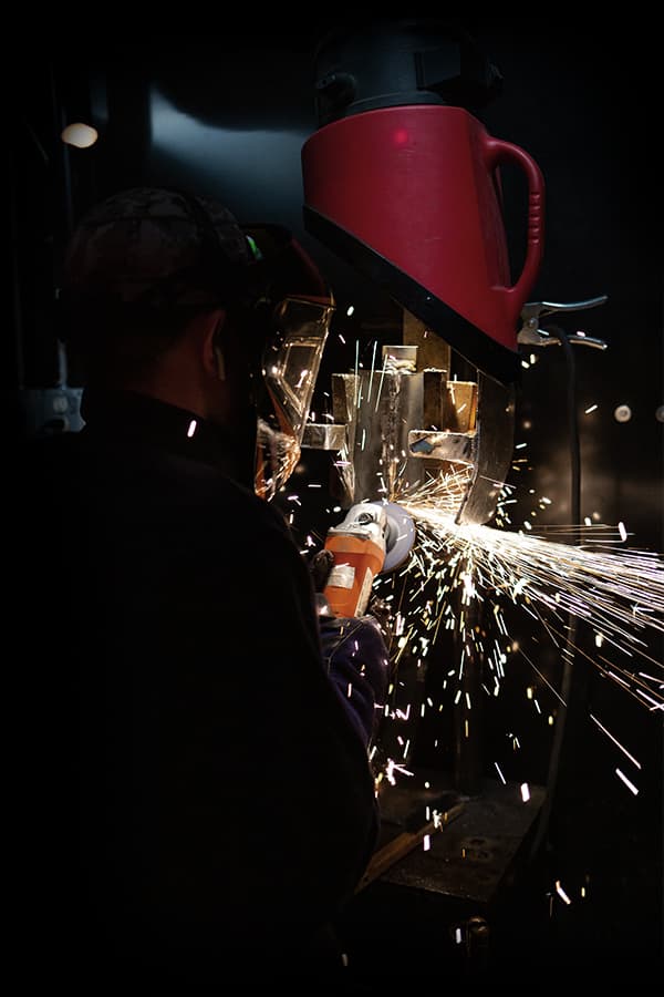 A Tidewater Tech welding student working with an angle grinder in the lab.