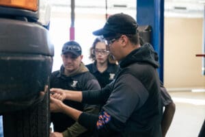 Automotive maintenance technician students working on a car.