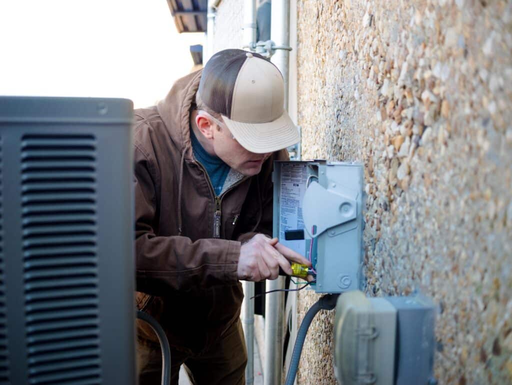HVAC training student performing hands-on maintenance on an outdoor electrical unit in Norfolk, Virginia.